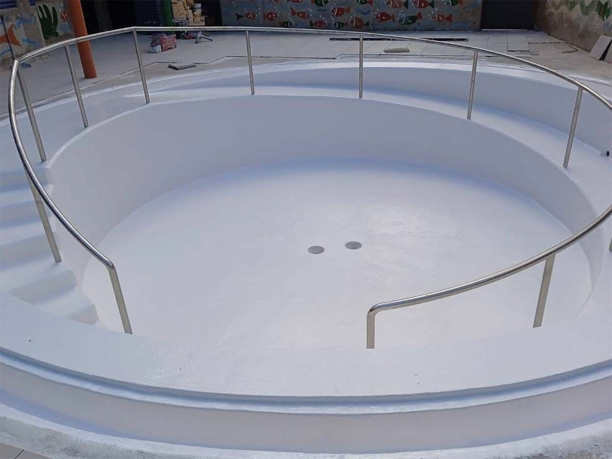 Una piscina blanca con una barandilla de acero inoxidable alrededor.