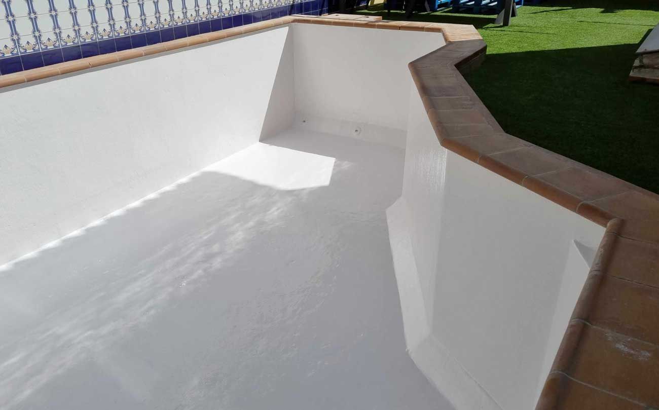 Una piscina blanca con una valla azul al fondo.