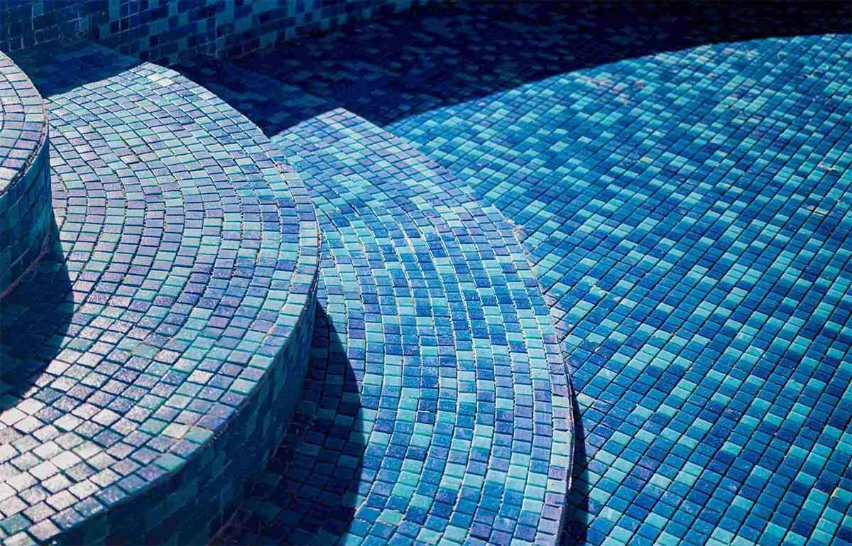 Una piscina con azulejos azules y escaleras que conducen a ella.
