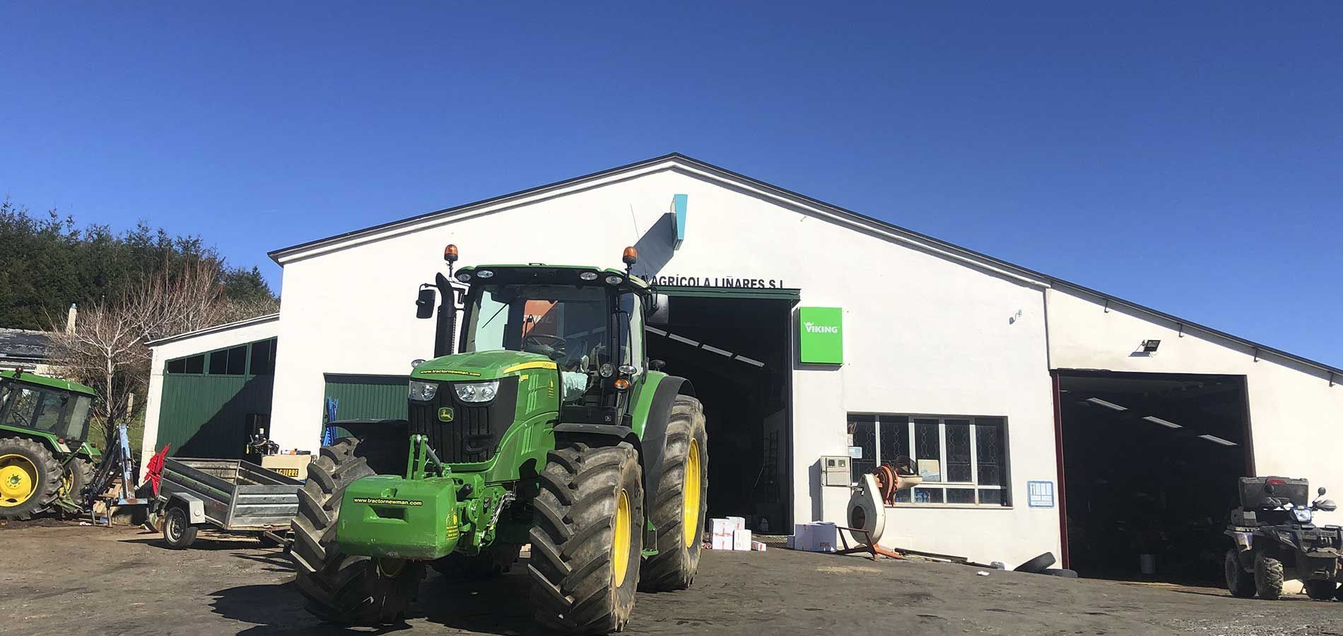 Un tractor verde está estacionado frente a un edificio blanco.