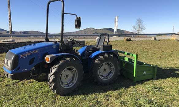 Un tractor azul está estacionado en un campo de hierba.