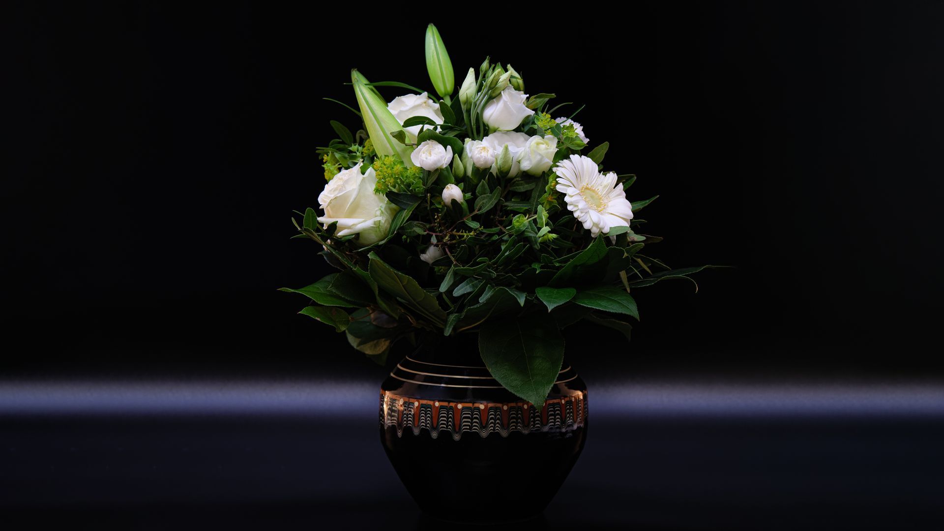 Fleurs blanches dans un vase noir, sur fond sombre.