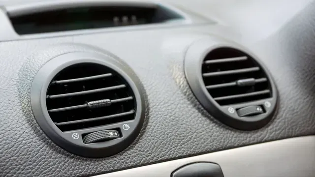 Dos rejillas de ventilación negras para el salpicadero del coche sobre un panel texturizado gris.