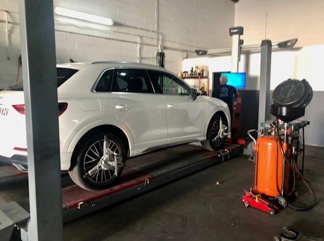 SUV blanco sobre un elevador de alineación de taller 