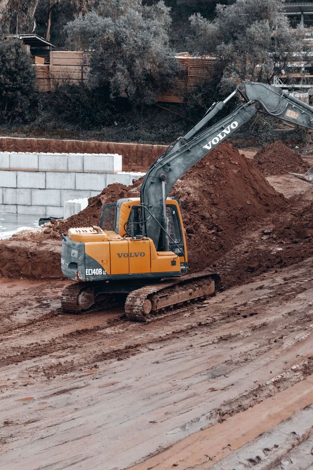 Une pelleteuse jaune creuse un talus boueux sur un chantier de construction.