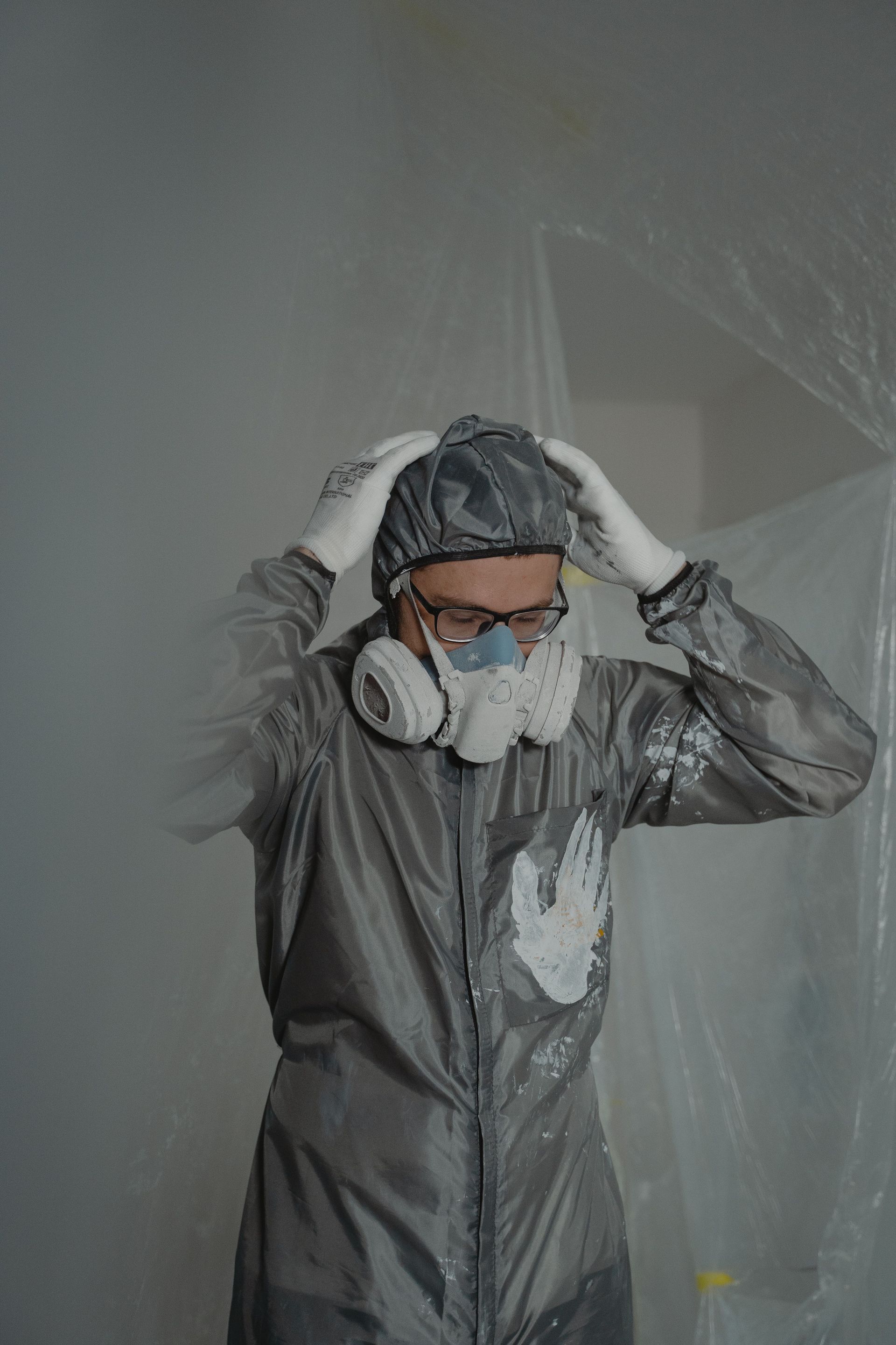 Pièce partiellement démolie avec plancher en bois apparent, débris et deux fenêtres dans un mur blanc