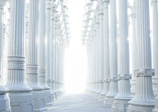 Una fila de columnas blancas que conducen a una luz.