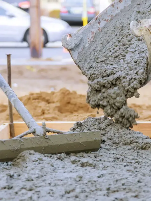 En una obra en construcción, se vierte hormigón gris húmedo desde una rampa hacia una estructura de madera