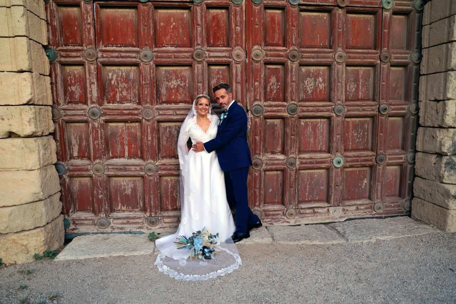 Una pareja de recién casados posa frente a una gran puerta de madera .