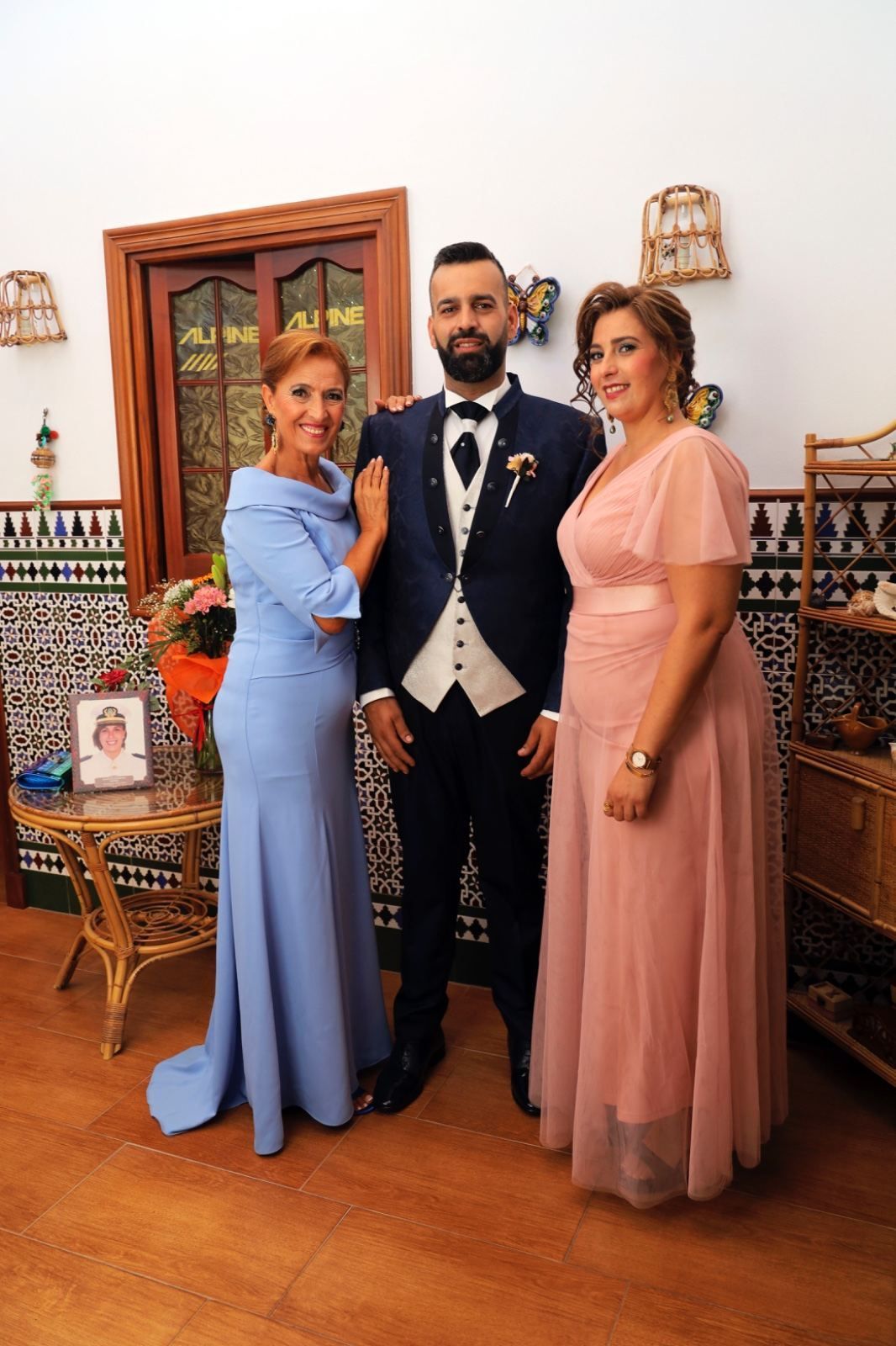 Un hombre con traje se encuentra entre dos mujeres. 