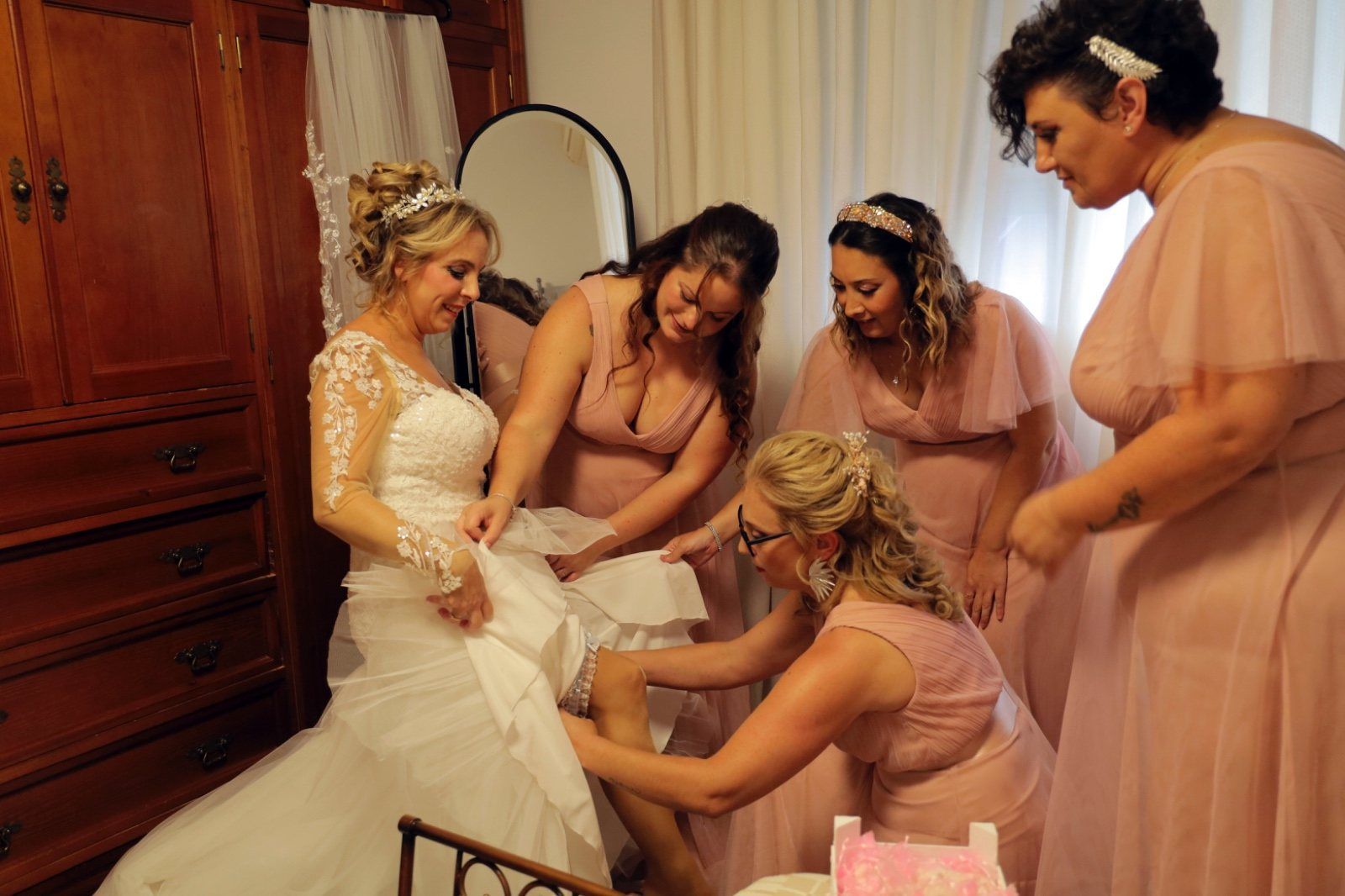 La novia, con un vestido blanco, es asistida por damas de honor con vestidos rosas. 
