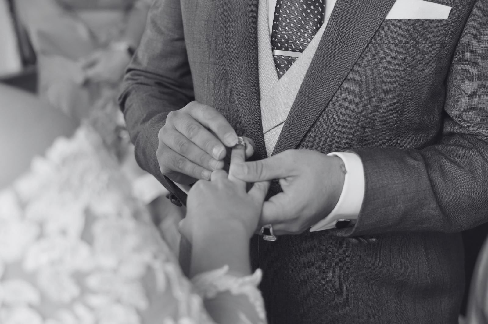 El novio coloca el anillo de bodas en el dedo de la novia durante una ceremonia. Blanco y negro.