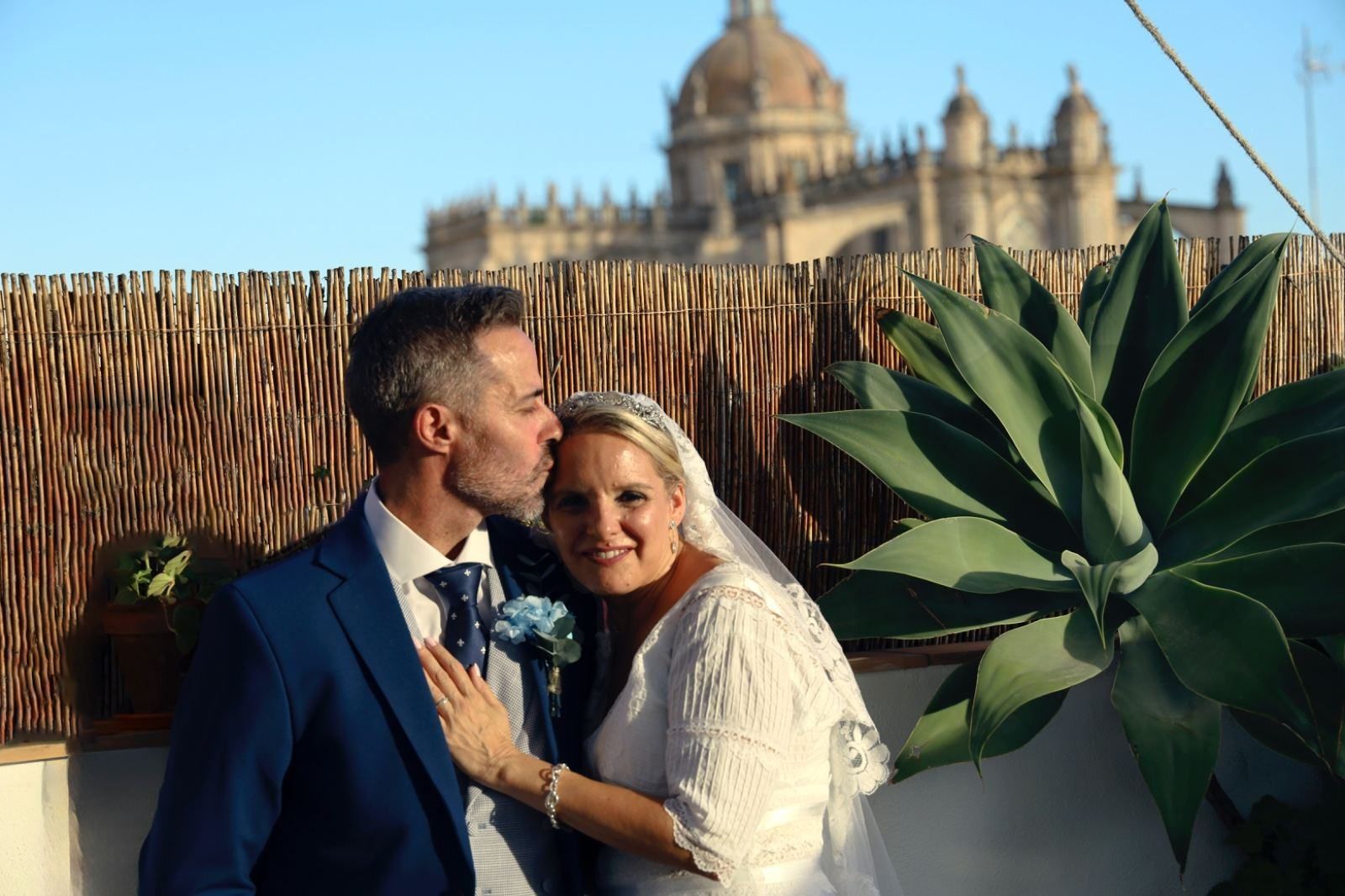 Los recién casados posan, el hombre besando la frente de la mujer.