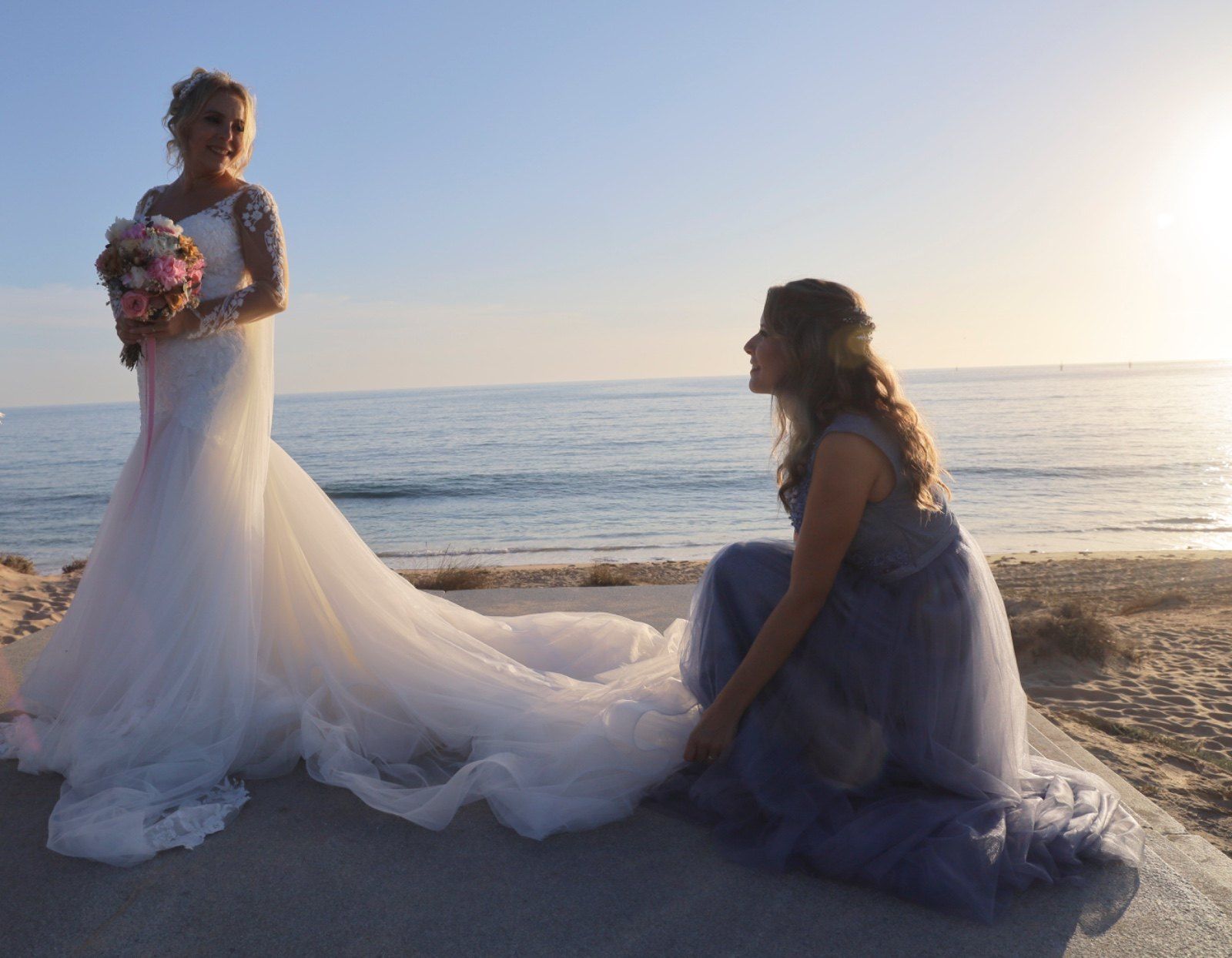 Una novia con un vestido blanco sonríe, sosteniendo un ramo. 