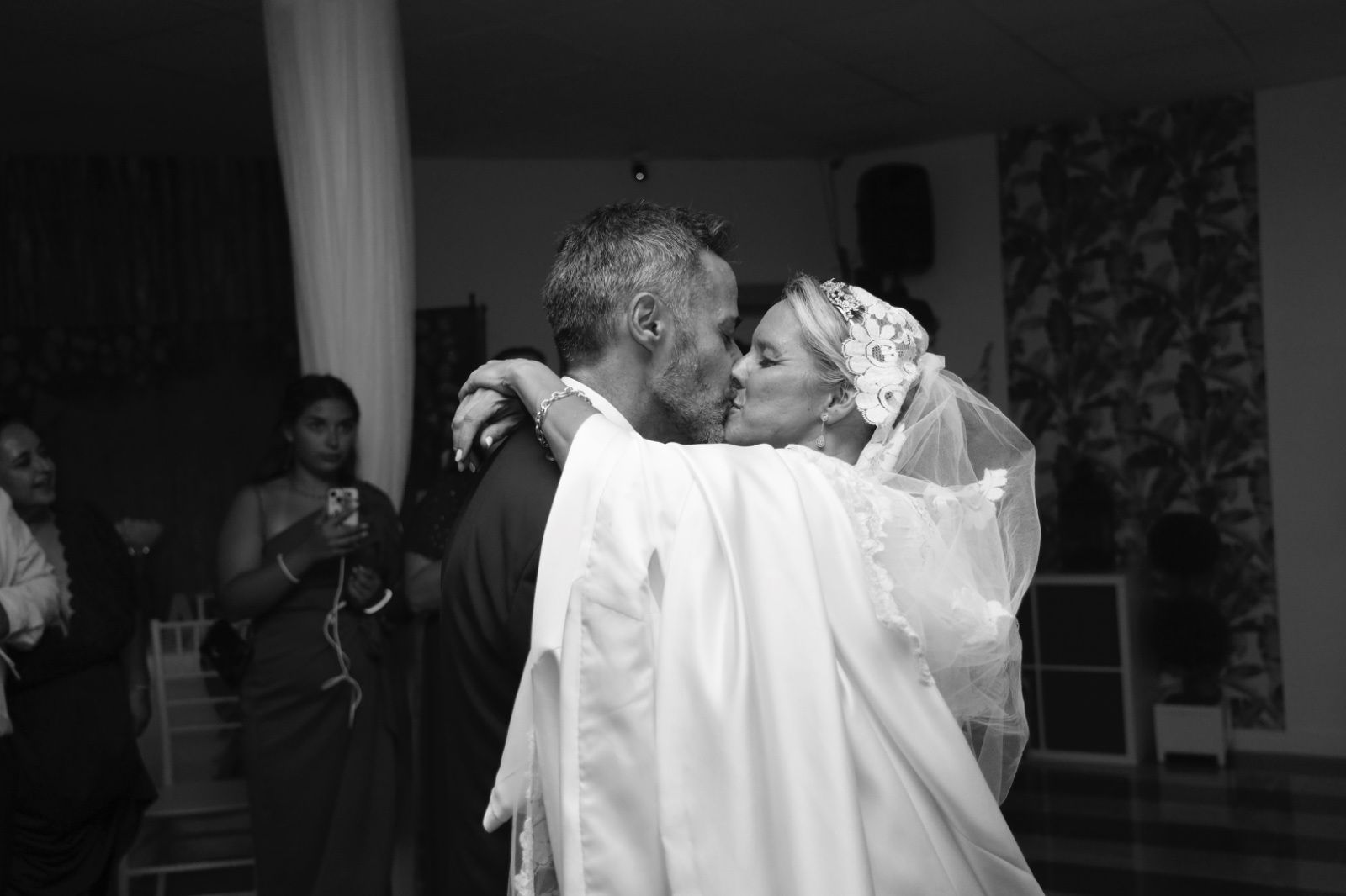 Los recién casados se besan mientras bailan en la recepción de su boda. 