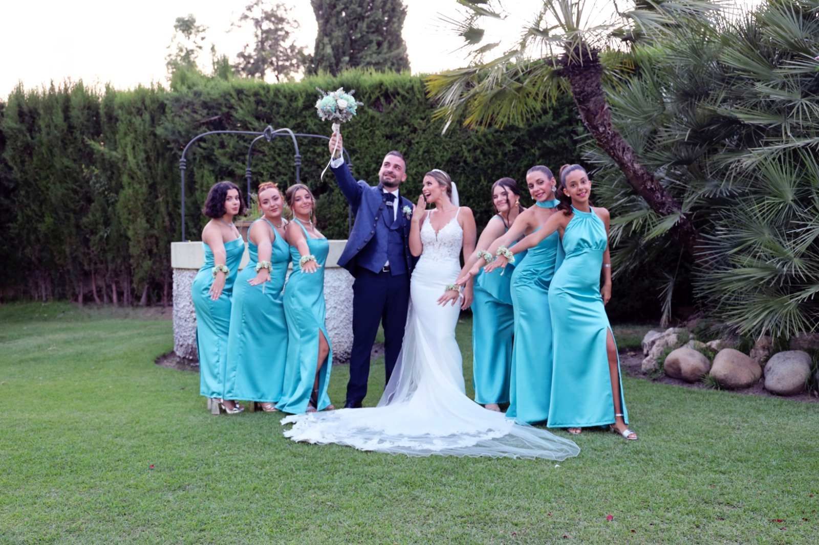 Los novios posan con las damas de honor en un jardín.