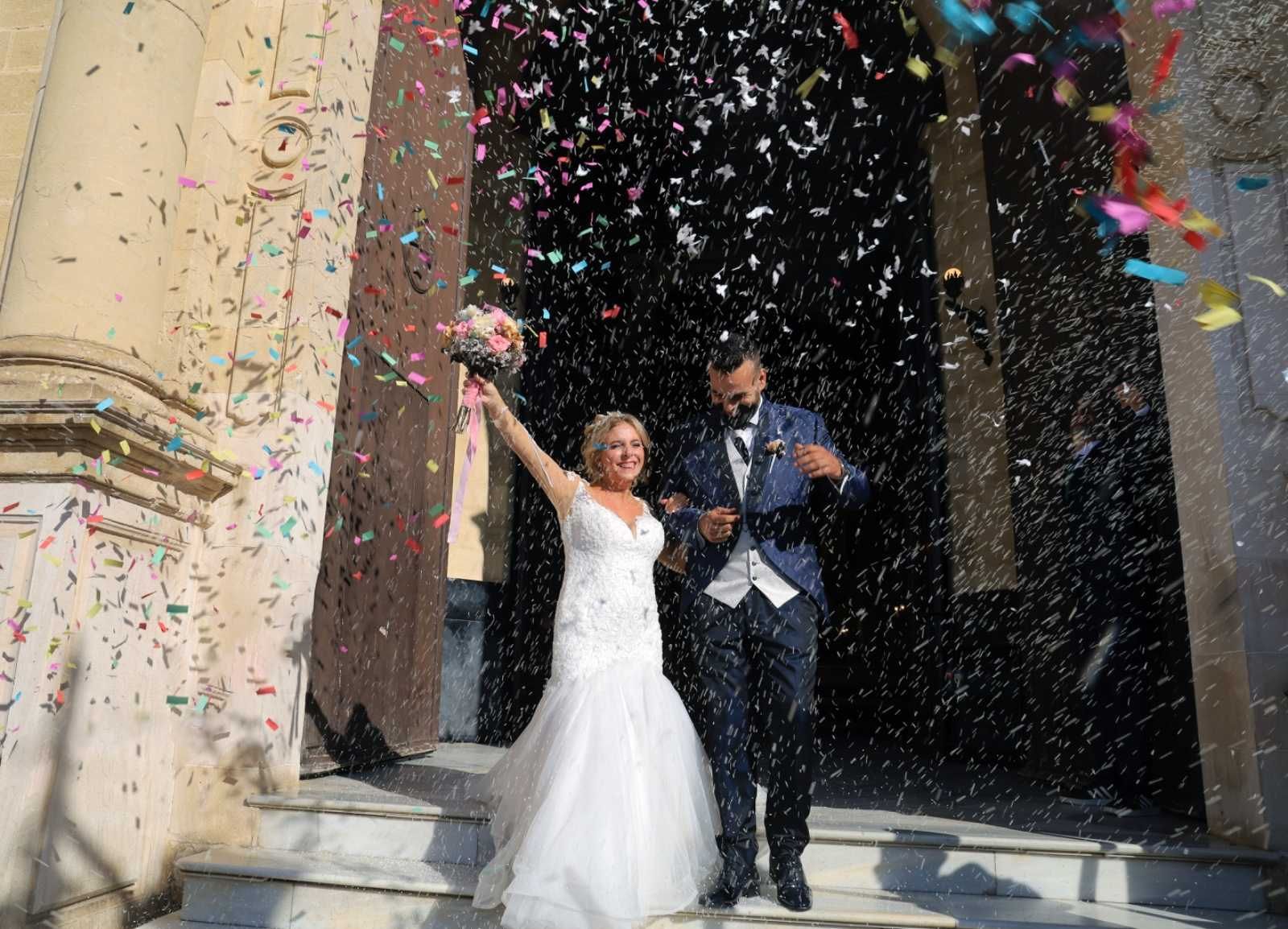 Los recién casados salen de una iglesia entre una lluvia de confeti.