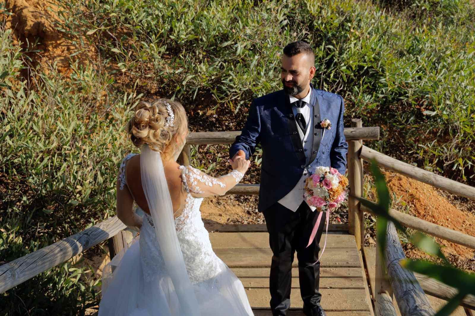 Los novios, tomados de la mano, caminan por un puente de madera.