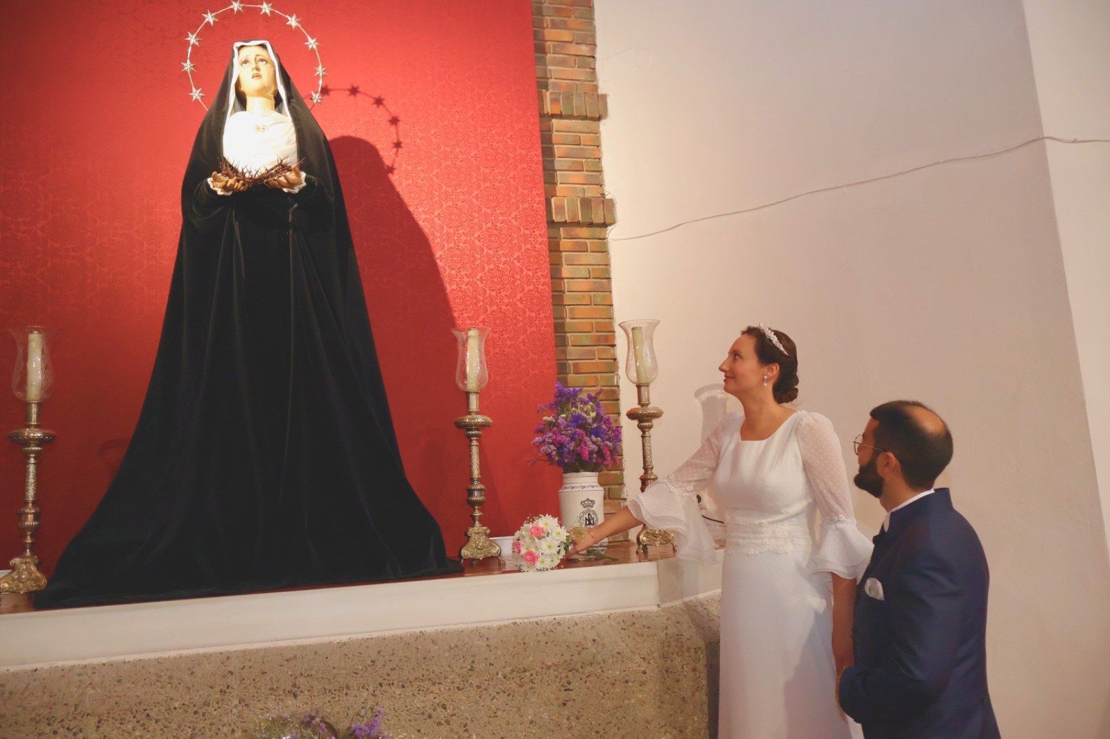 Una pareja de recién casados contempla una estatua de la Virgen María.