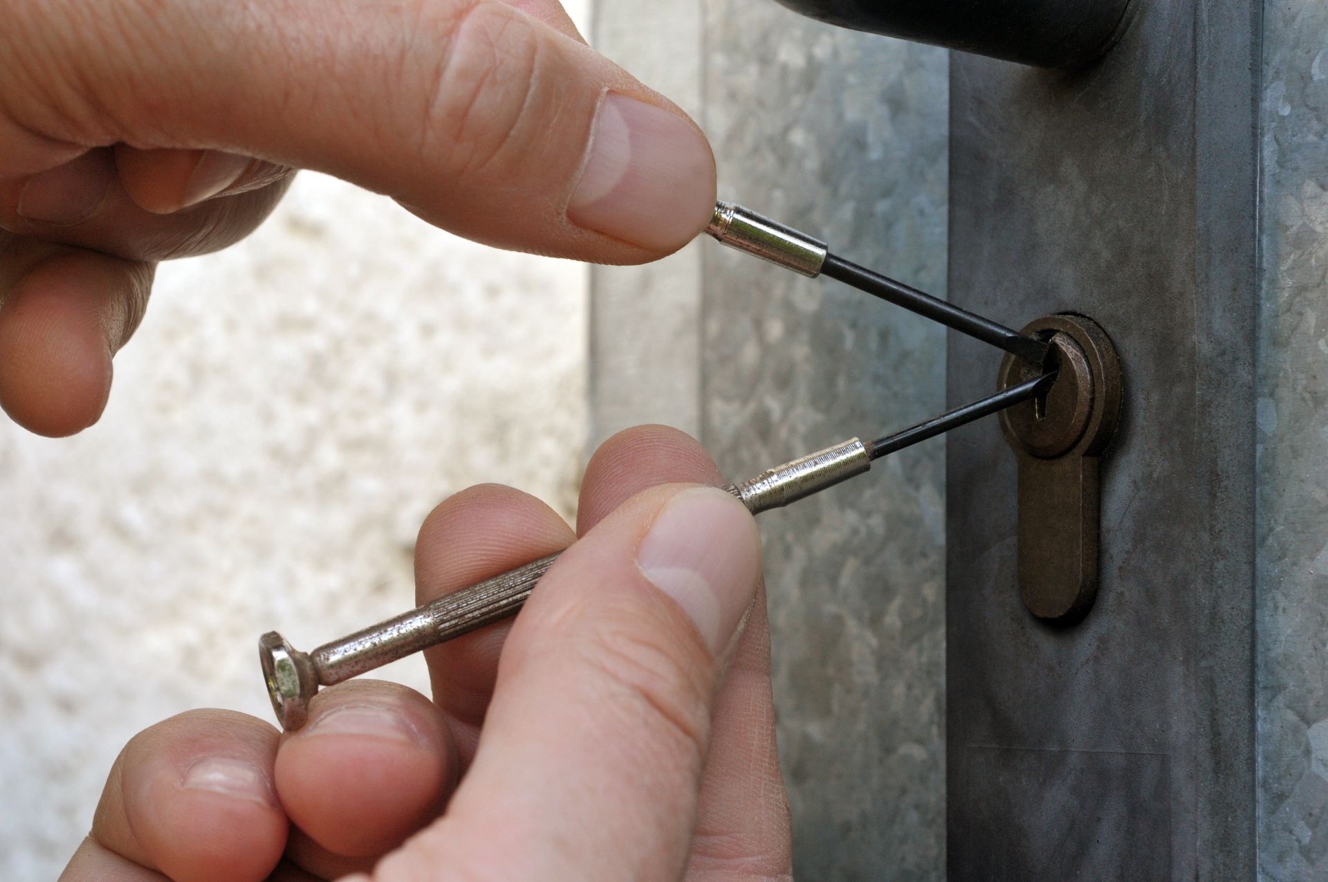 Des mains manipulent des clés pour verrouiller un loquet de porte métallique.