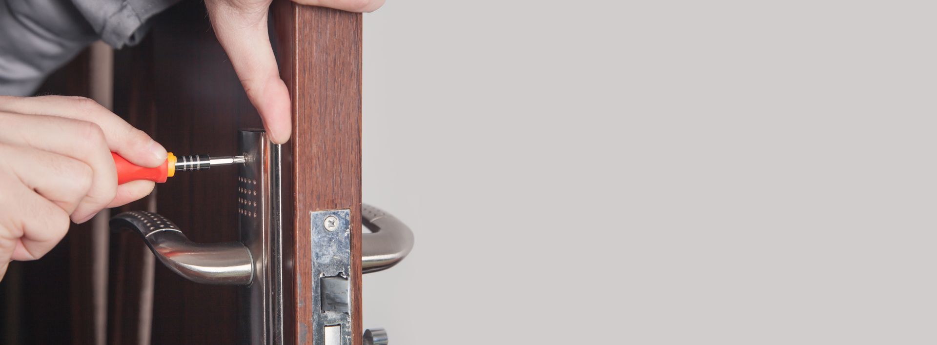 Serrer à la main une vis sur une charnière de porte d'armoire avec un tournevis