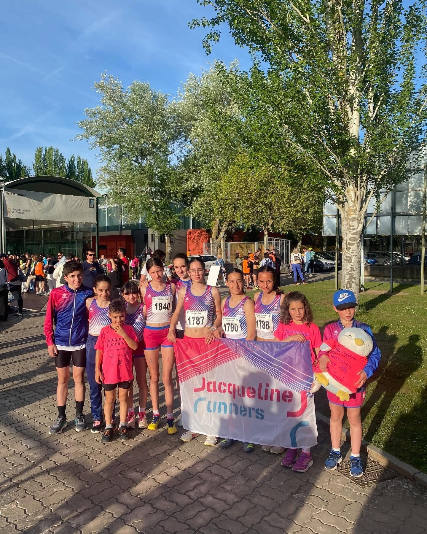 Un grupo de jóvenes corredores con camisetas de competición posa al aire libre 