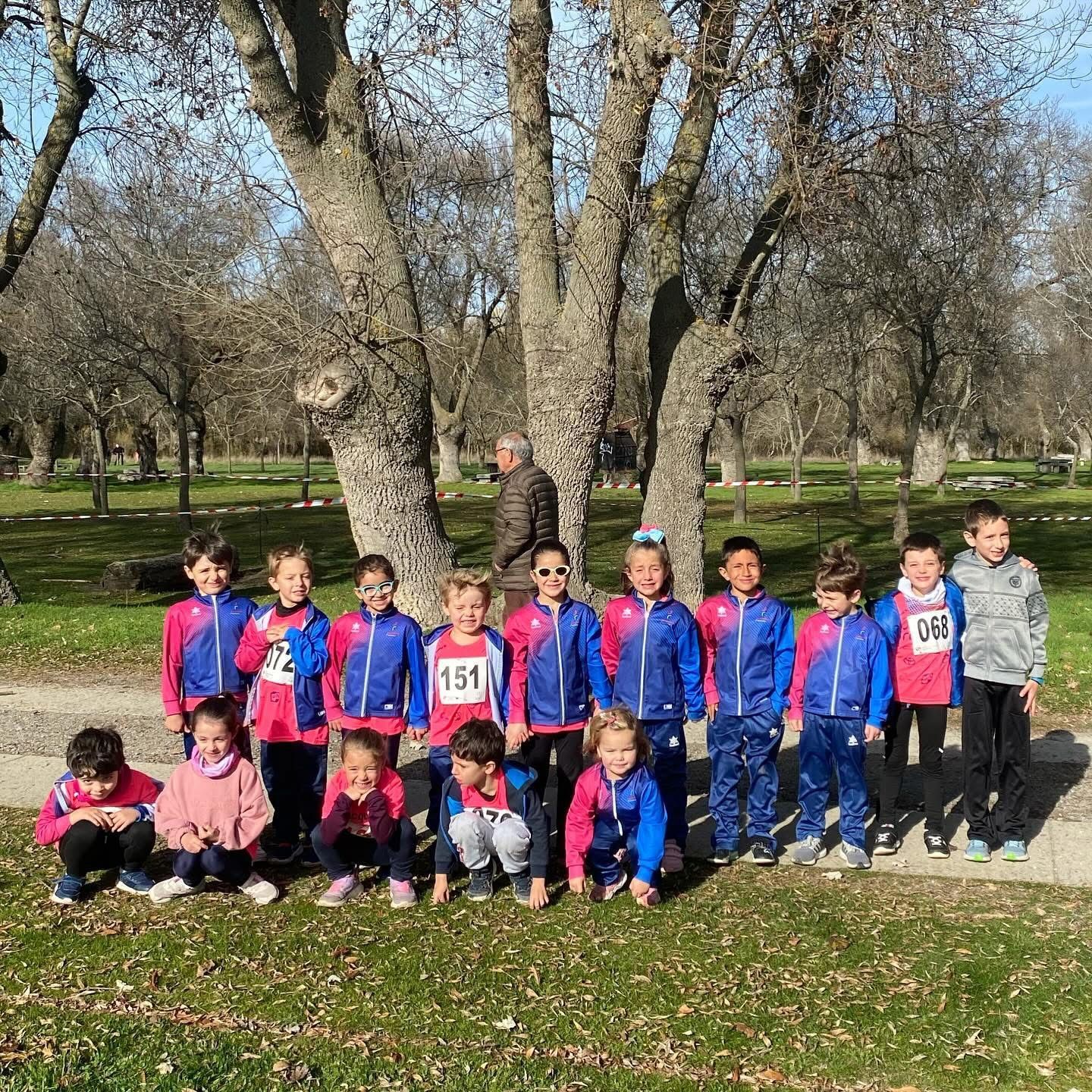 Un grupo de niños en chándal posa frente a un árbol en un parque.