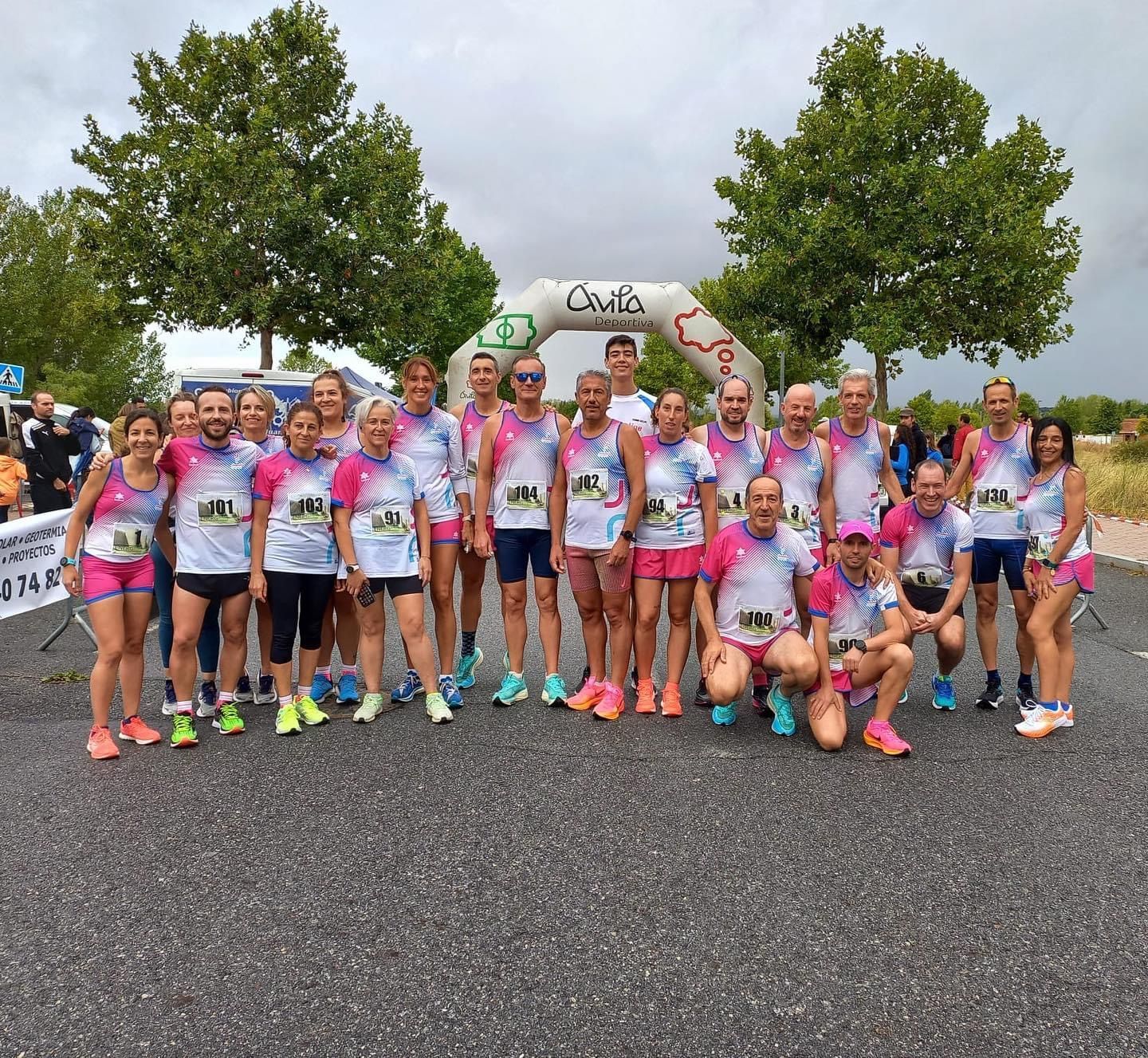 Un grupo de corredores con camisetas rosas y blancas a juego posan en la línea de salida de una carrera