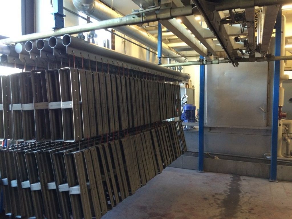 Metallboxen hängen an einem Förderband, wahrscheinlich in einer Fabrik.