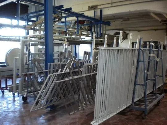 Metallgerüstkomponenten in einer Fabrik. Mehrere Einheiten sind gestapelt, einige hängen darüber.