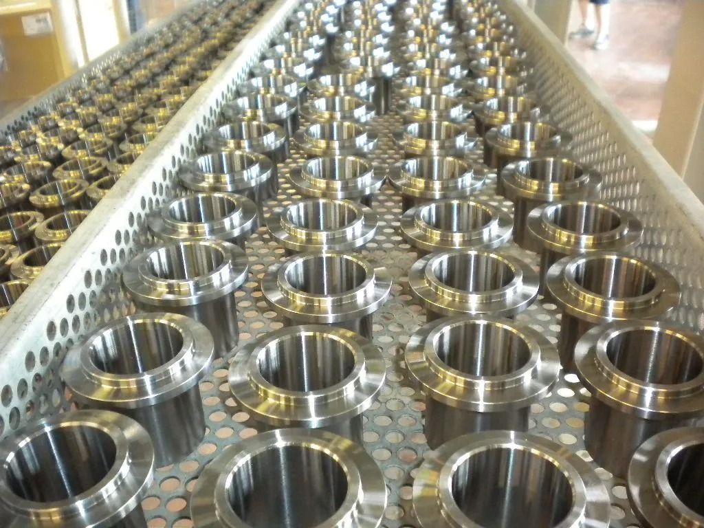 Reihen glänzender, zylindrischer Metallteile, möglicherweise industriell, ordentlich auf einem Metalltablett angeordnet.