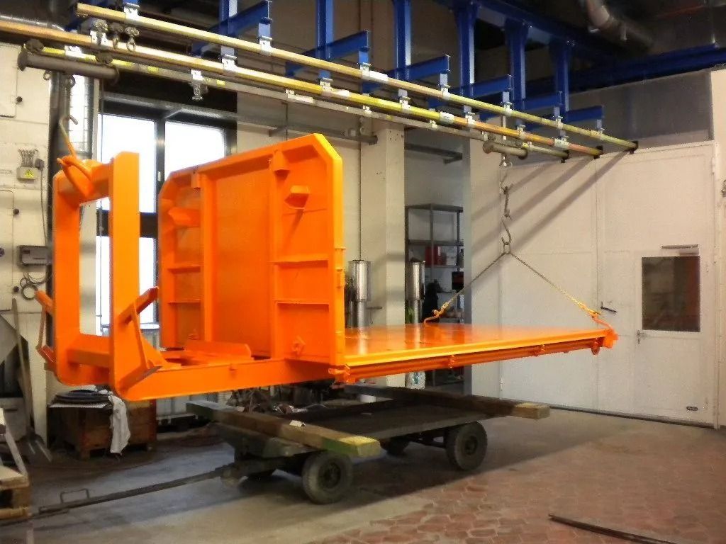Orangefarbene, an Schienen aufgehängte Industrieplattform aus Metall in einer Fabrik.