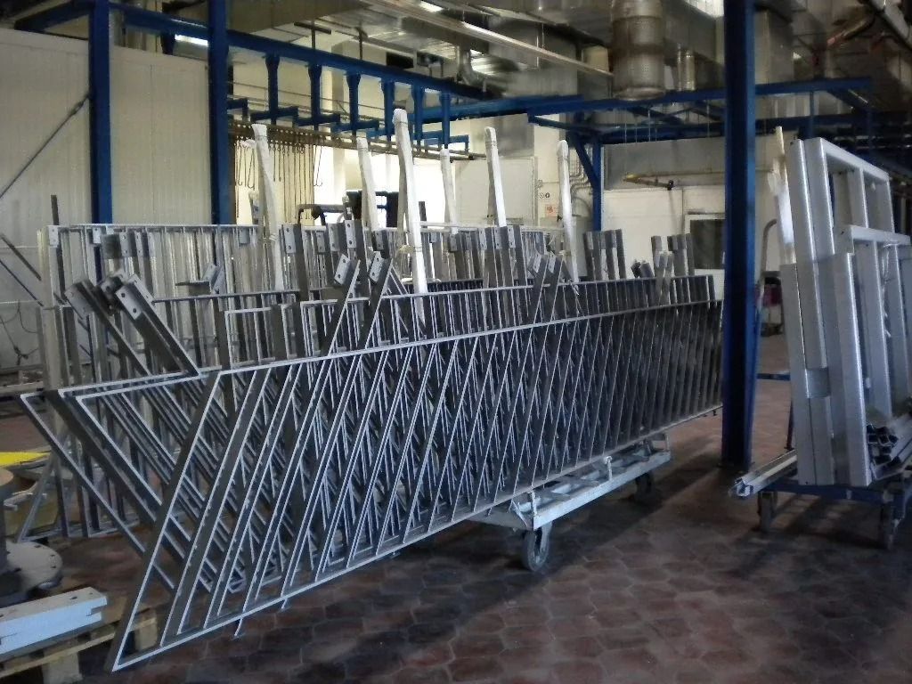 Metallische Absperrgitter zur Personenkontrolle sind in einer Industrieanlage gestapelt und bereit für den Transport.