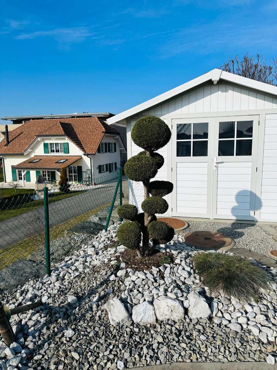 Un hangar blanc avec un arbre devant