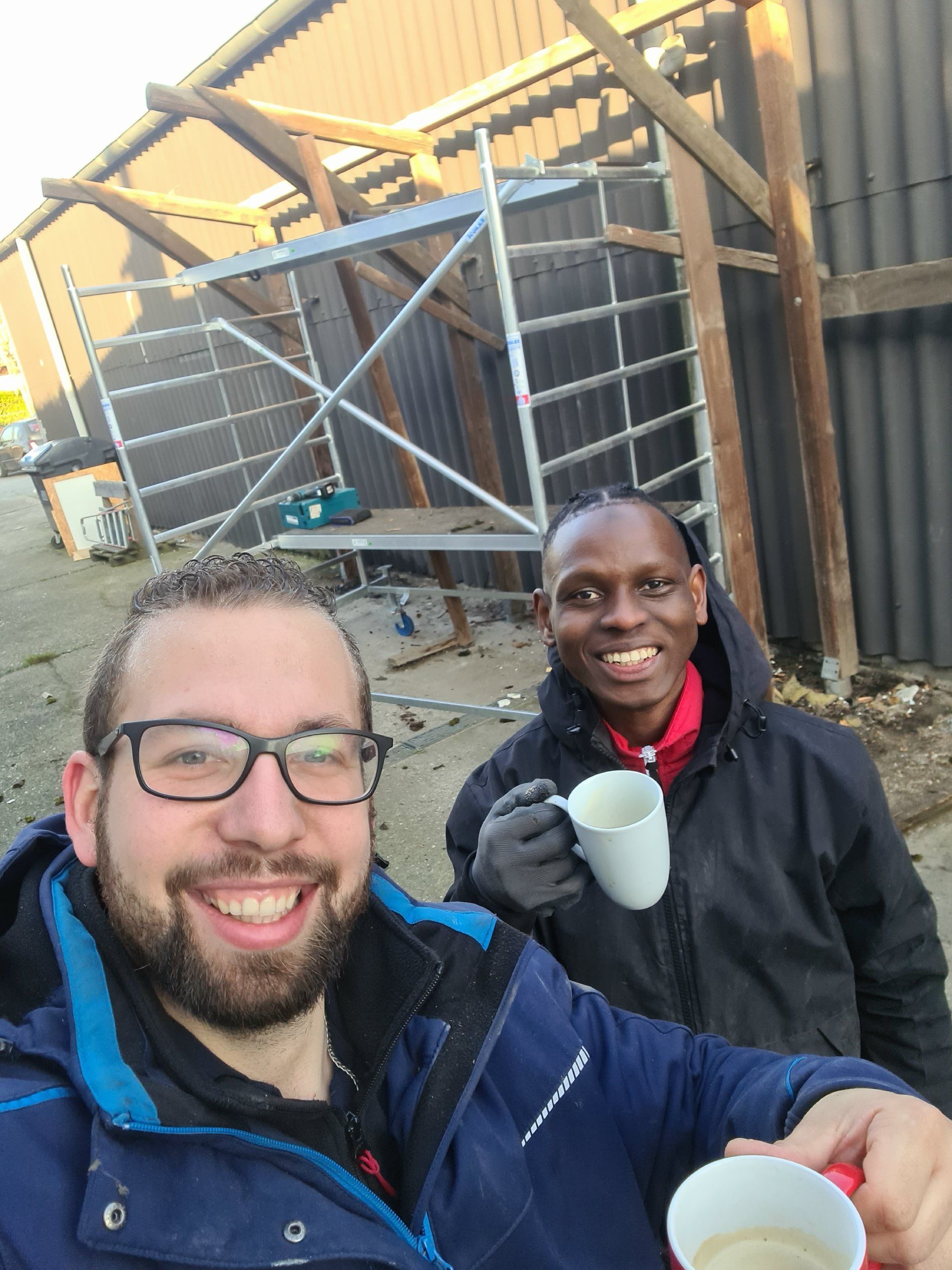 Zwei Männer stehen nebeneinander und halten Tassen Kaffee.