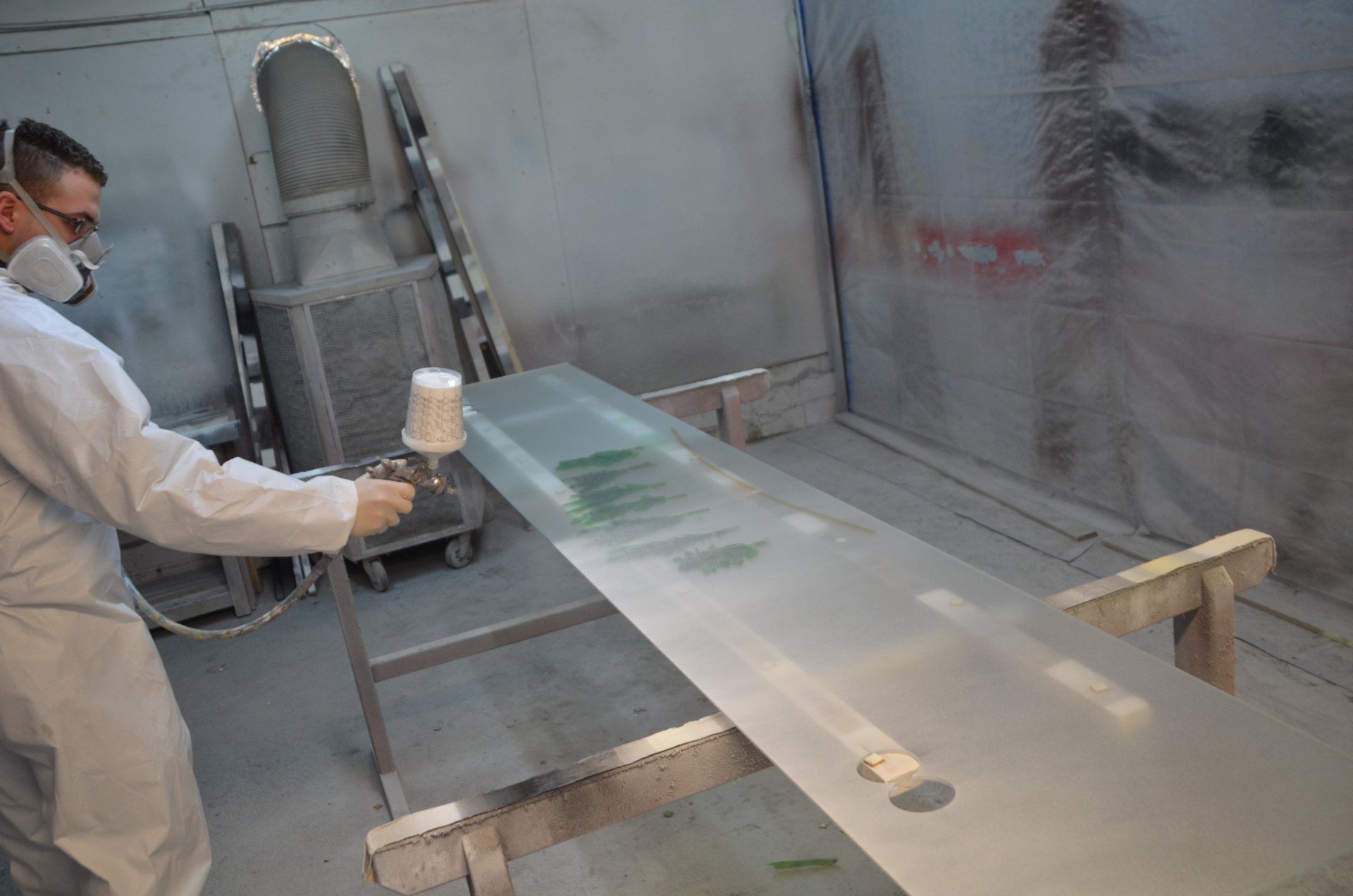 Ein Mann besprüht ein Glas in einem Raum mit Farbe.