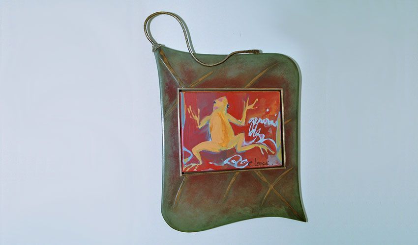 Un cadre en forme de feuille vu de face et accroché sur un mur blanc