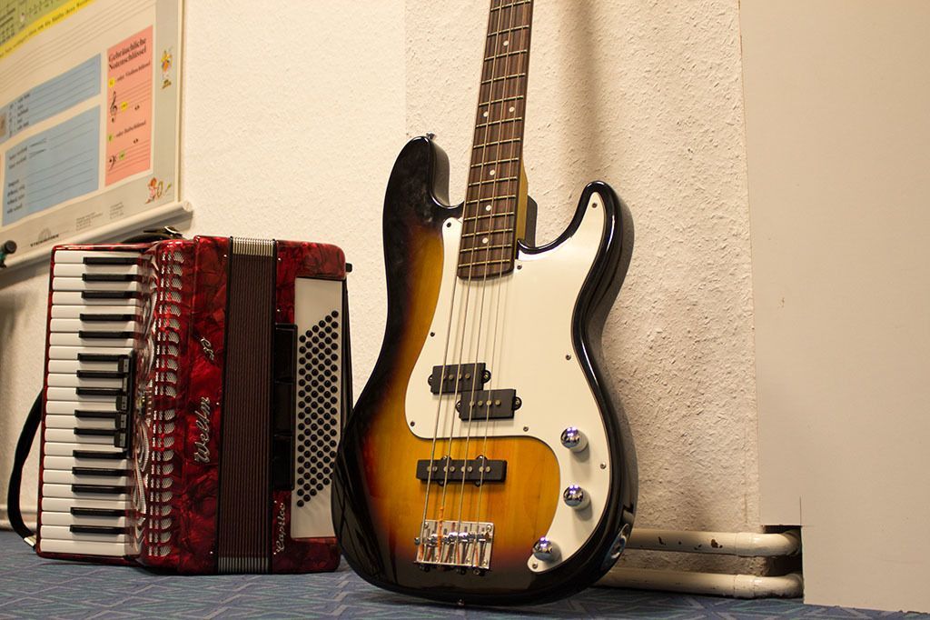 Eine Gitarre lehnt neben einem Akkordeon an einer Wand