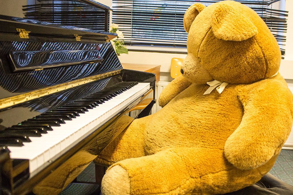 Ein Teddybär sitzt vor einem Klavier.