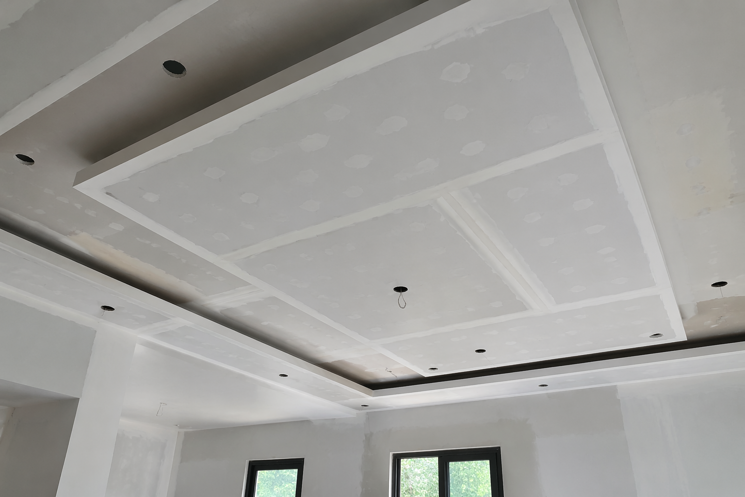 Pièce intérieure en construction avec des panneaux de plaques de plâtre, des outils, un échafaudage.