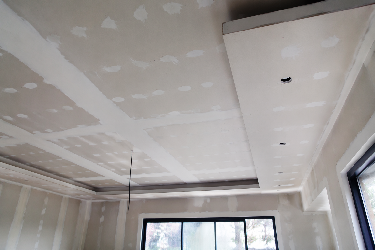 Pièce intérieure en construction avec des panneaux de plaques de plâtre, des outils, un échafaudage.