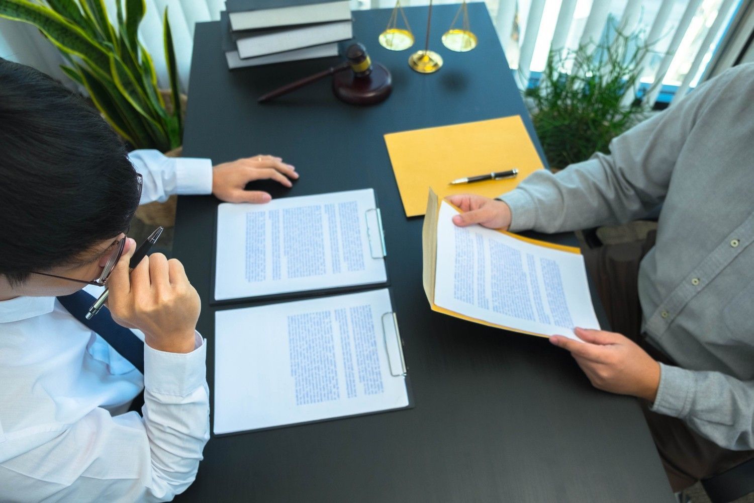 Dos personas están sentadas en un escritorio revisando documentos legales en un bufete de abogados