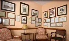 En una sala de espera con numerosos documentos enmarcados en las paredes, hay dos sillas 