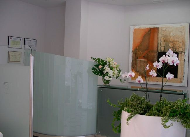 Mostrador de recepción con flores blancas y arte abstracto.