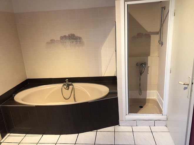Une baignoire d'angle et une douche à côté