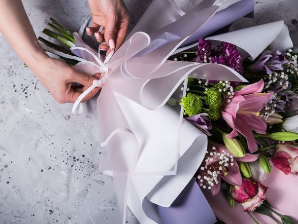 Une fleuriste arrange des fleurs colorées. Des mains trient des fleurs dans une boutique.