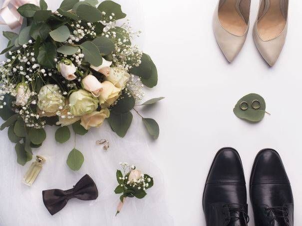 Tenue de mariage : bouquet, chaussures, alliances, nœud papillon, boutonnière, parfum et voile de robe sur fond blanc.