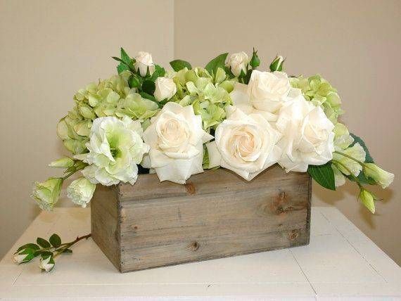 Des roses blanches et des hortensias verts dans une boîte en bois rustique.