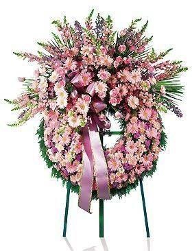 Couronne de fleurs roses et lavande sur un support vert, avec un ruban rose.