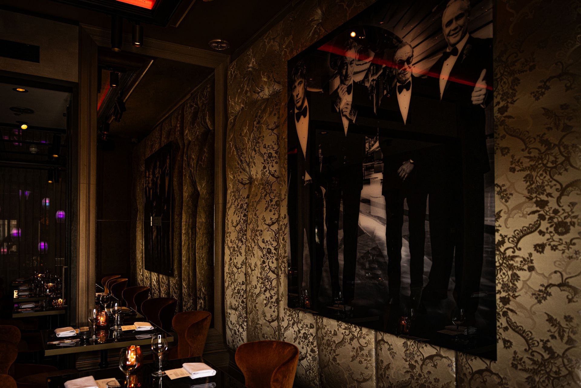Dimly lit restaurant with patterned wallpaper, hanging bunting, and window reflections at night